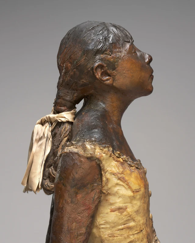 Detail of the head, neck, shoulders, and chest of the same wax sculpture. Wax covers parts of the hair and bodice; individual hairs, fine horizontal fabric lines, and folds in the pale ribbon remain visible.